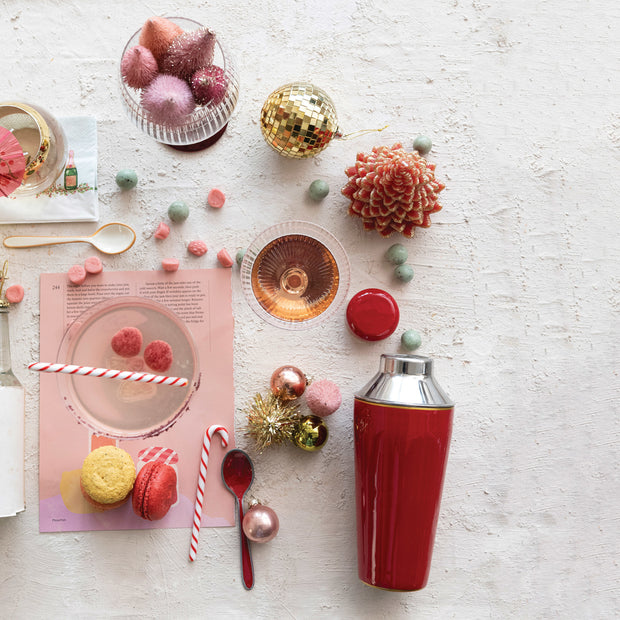 Decorative table setting with a red shaker, candy canes, and Christmas ornaments on a light surface.