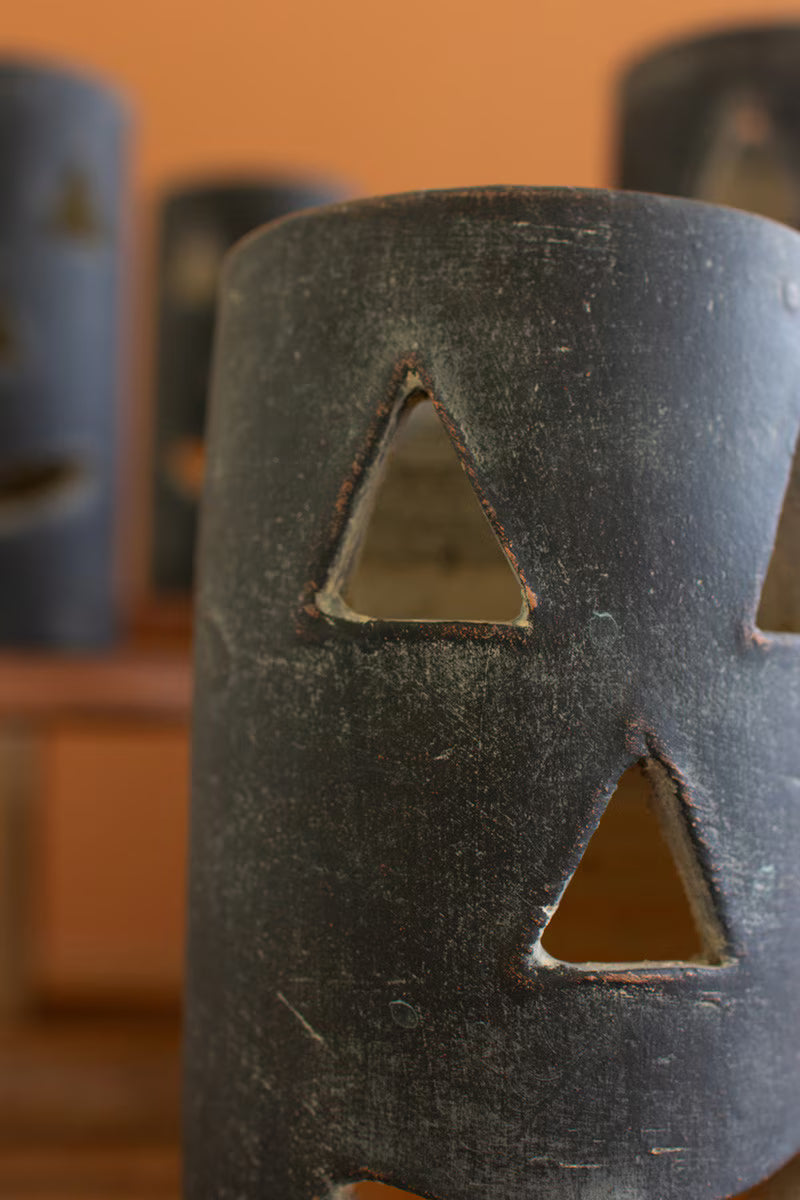 Black ceramic vase with triangular cutouts on a blurred background