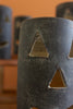 Black ceramic vase with triangular cutouts on a blurred background