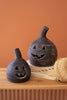 Two black ceramic jack-o'-lanterns on a wooden surface with an orange background