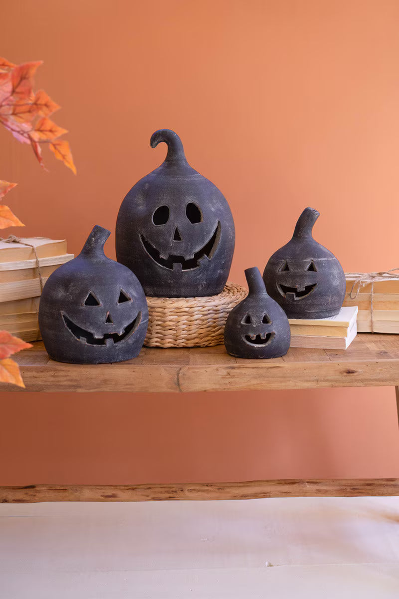 Black jack-o'-lantern decorations on a wooden surface with an orange wall background