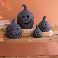 Black jack-o'-lantern decorations on a wooden surface with an orange wall background