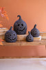 Black jack-o'-lantern decorations on a wooden surface with an orange wall background
