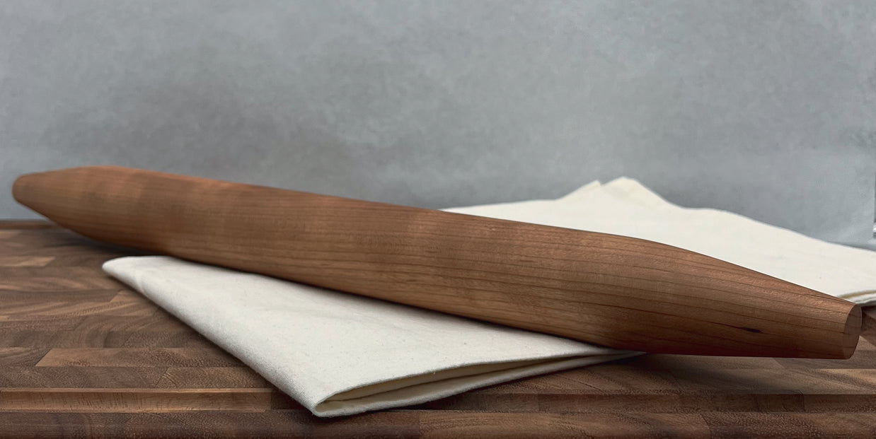Wooden rolling pin on a wooden surface with a gray background