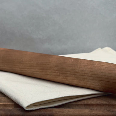 Wooden rolling pin on a wooden surface with a gray background