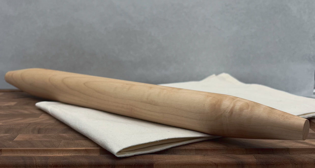 Wooden rolling pin on a wooden surface with a gray background