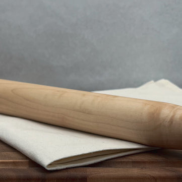 Wooden rolling pin on a wooden surface with a gray background