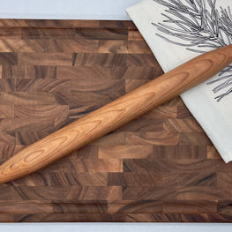 Wooden cutting board with a rolling pin on a white surface
