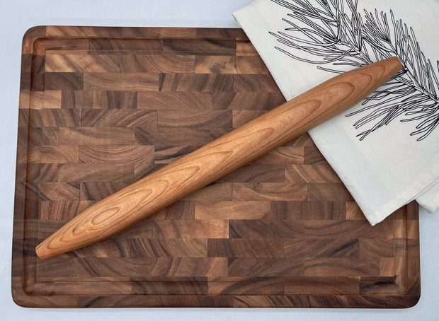 Wooden cutting board with a rolling pin on a white surface