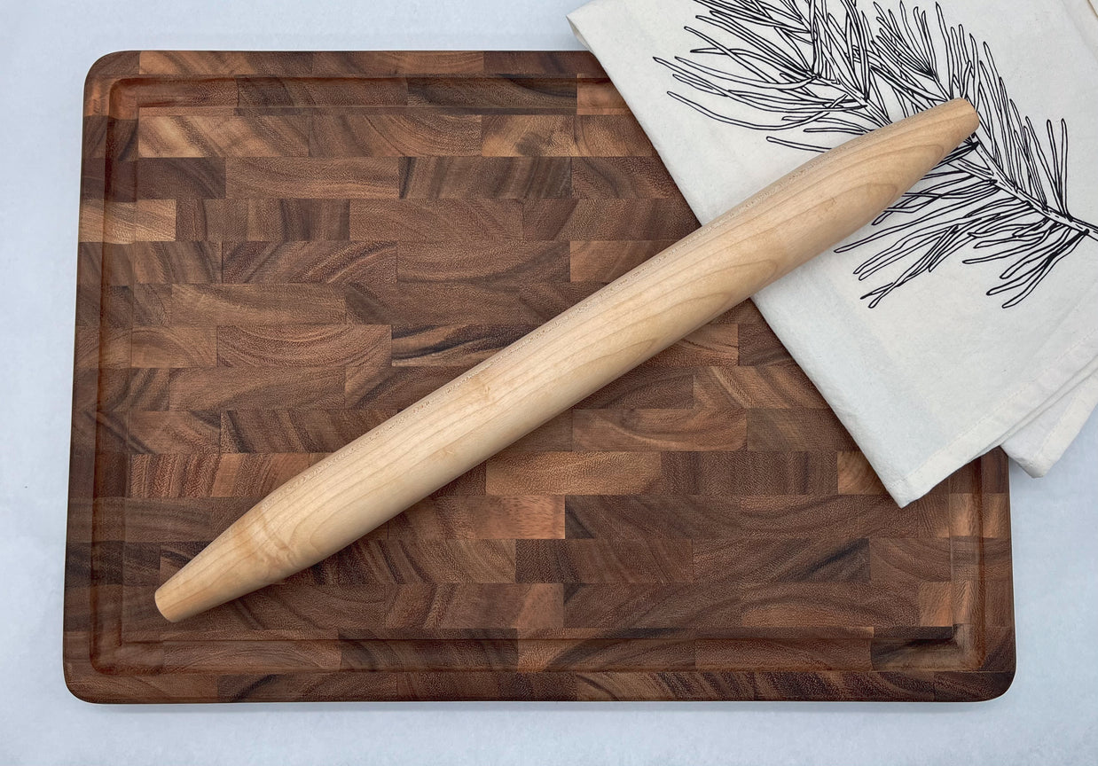 Wooden cutting board with a rolling pin and a towel on a light background