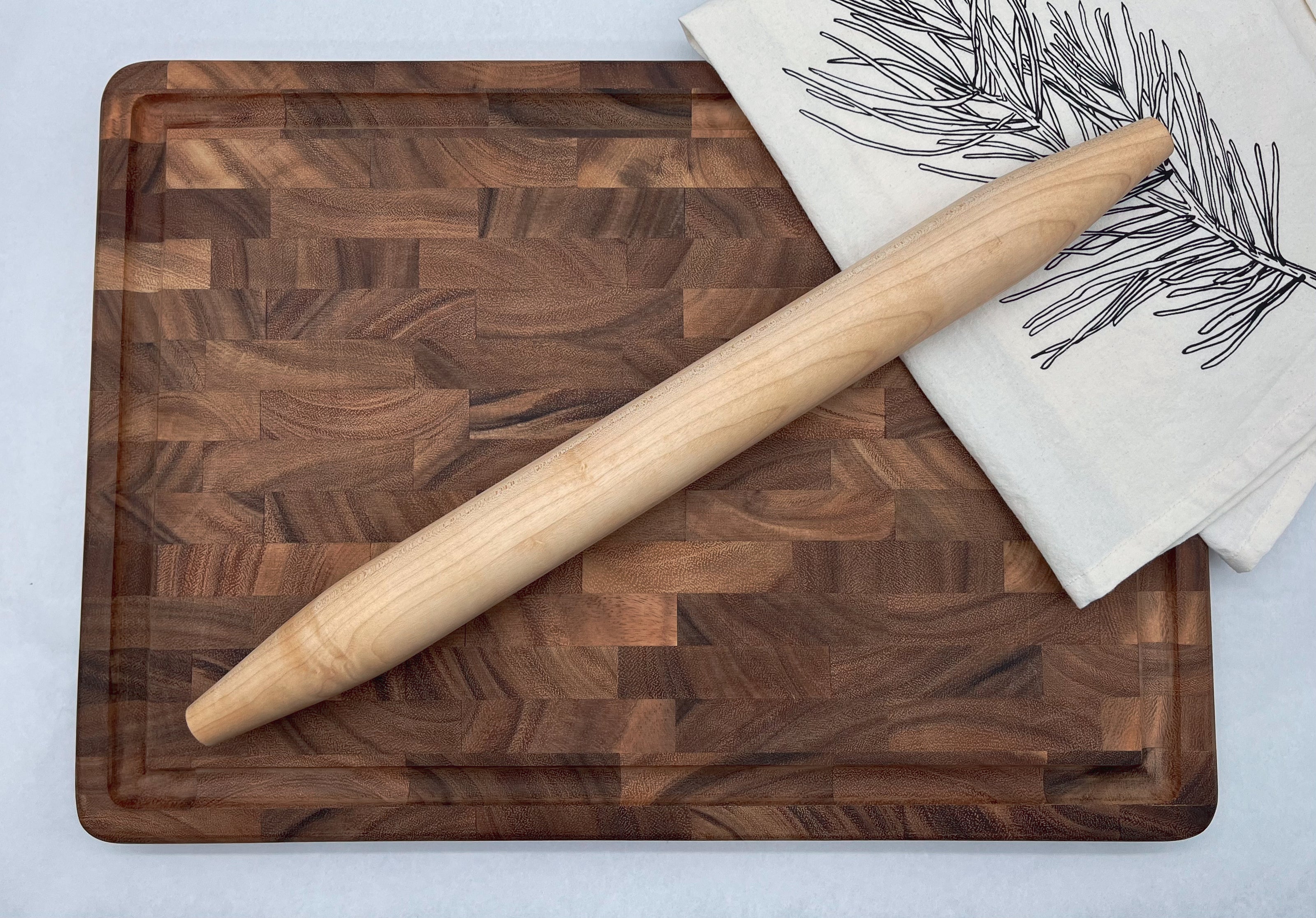 Wooden cutting board with a rolling pin and a towel on a light background