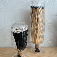 Two clear glass containers with hair extensions on a light wooden surface and light gray background.
