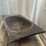 Rectangular wooden bowl on a wooden surface with a white curtain background