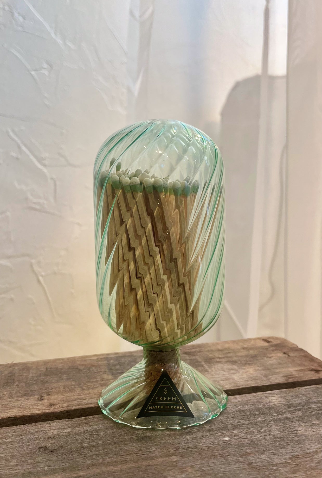 Green glass match holder with matches on a wooden surface