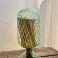 Green glass match holder with matches on a wooden surface