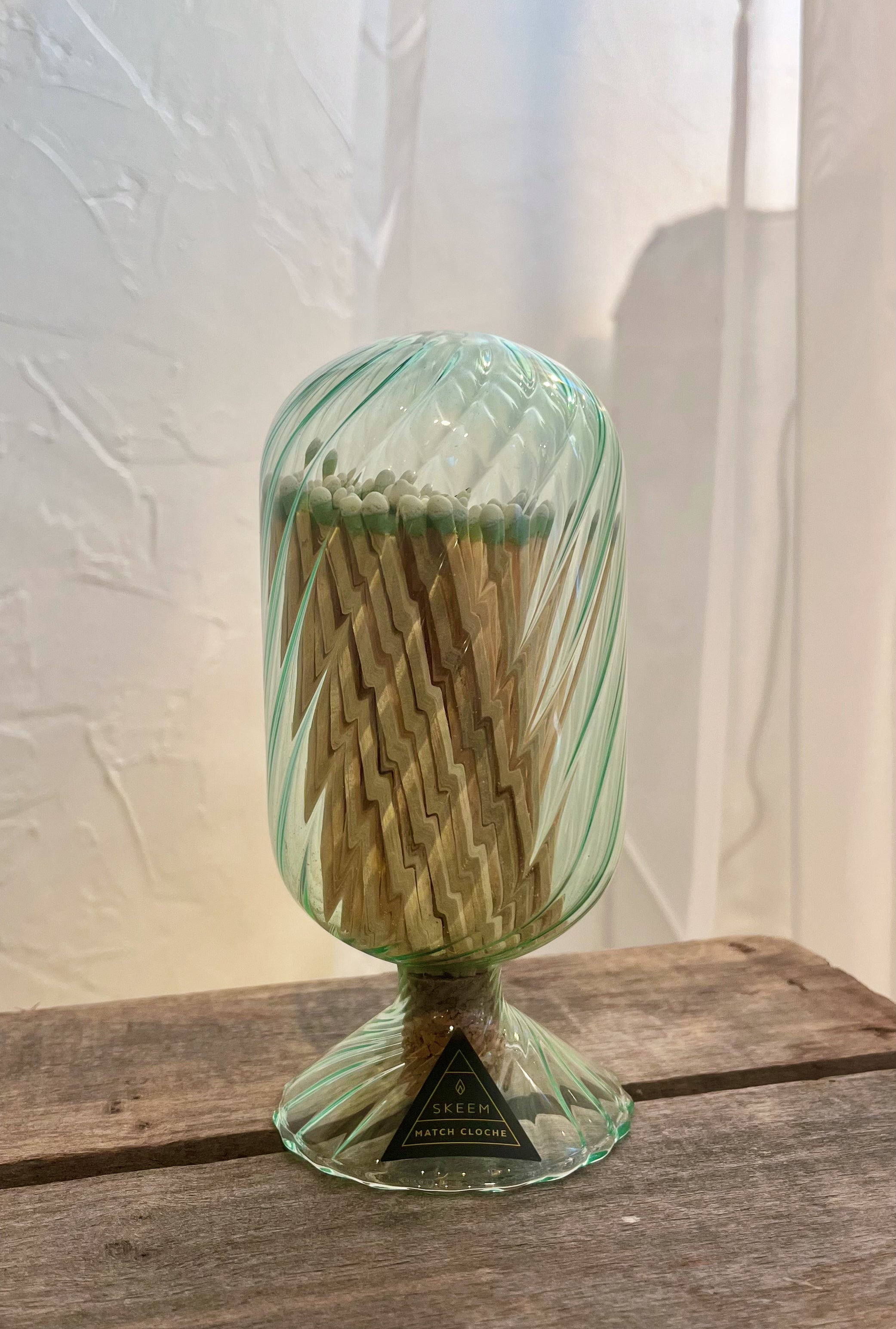 Green glass match holder with matches on a wooden surface