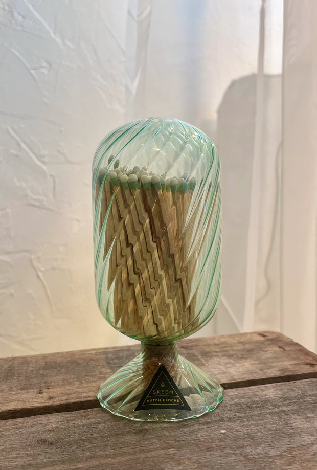 Green glass match holder with matches on a wooden surface