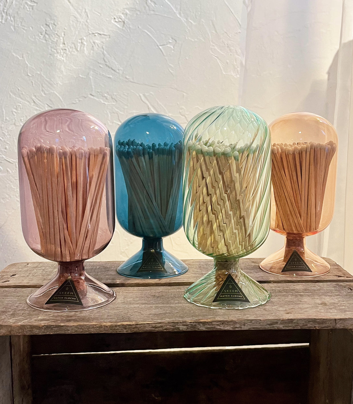 Four colorful match holders with matches on a wooden surface.