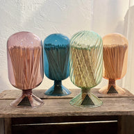 Four colorful match holders with matches on a wooden surface.