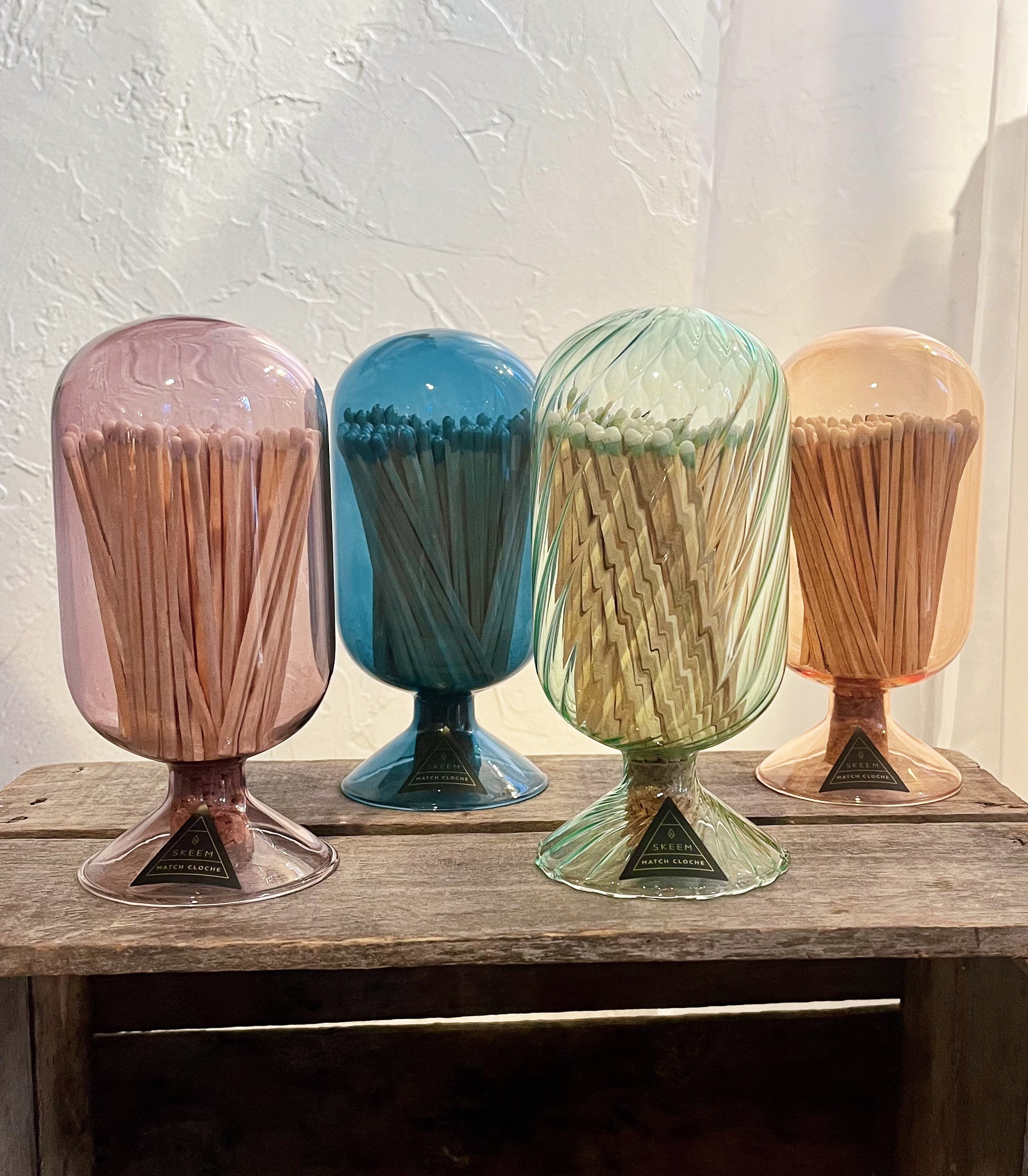 Four colorful match holders with matches on a wooden surface.
