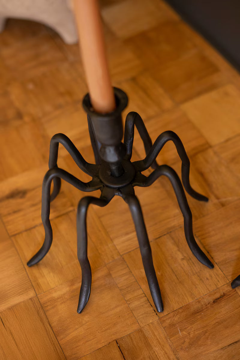 Black spider-shaped umbrella stand on a wooden floor