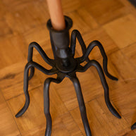 Black spider-shaped umbrella stand on a wooden floor