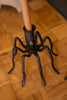 Black spider-shaped umbrella stand on a wooden floor