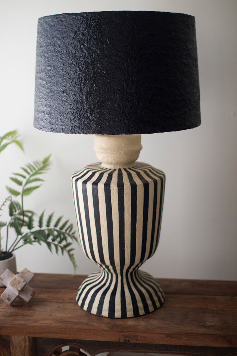 Decorative lamp with black and white striped base and black textured shade on a wooden surface.