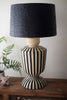 Decorative lamp with black and white striped base and black textured shade on a wooden surface.