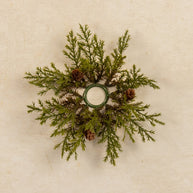 Decorative wreath with greenery and pinecones on a beige background
