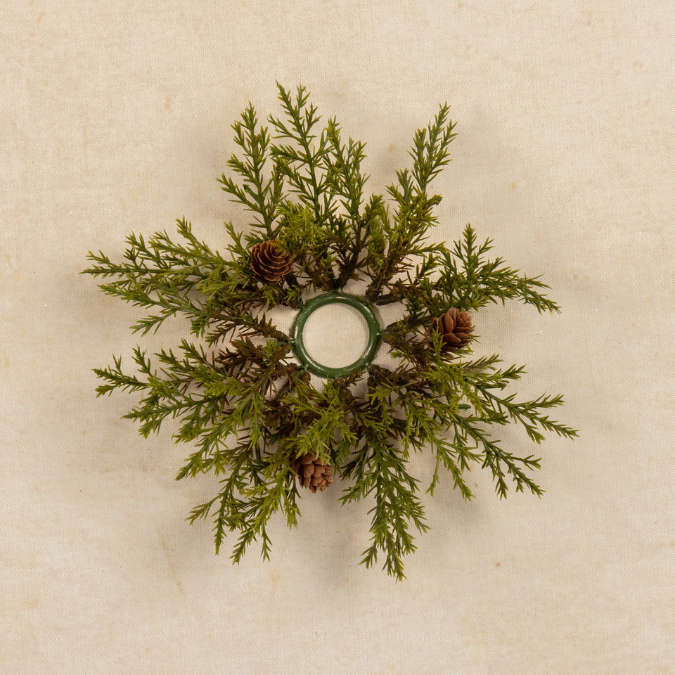Decorative wreath with greenery and pinecones on a beige background