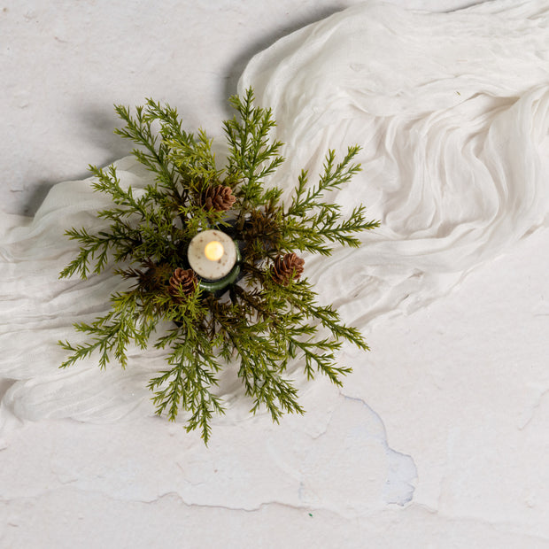 Decorative arrangement with greenery and a candle on a textured white surface