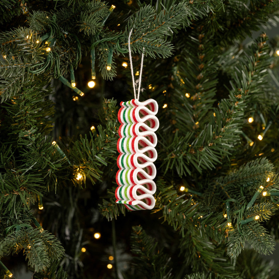 Decorative candy cane ornament on a Christmas tree with lights.