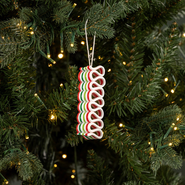 Decorative candy cane ornament on a Christmas tree with lights.