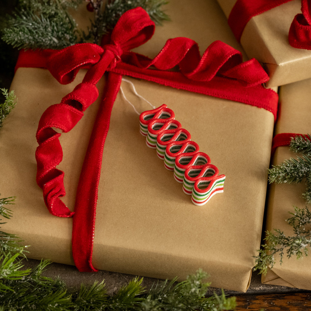 Gift wrapped in brown paper with a red ribbon, surrounded by greenery.