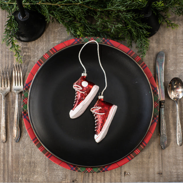 Red and white sneaker ornaments on a black plate with plaid rim, surrounded by Christmas decorations.