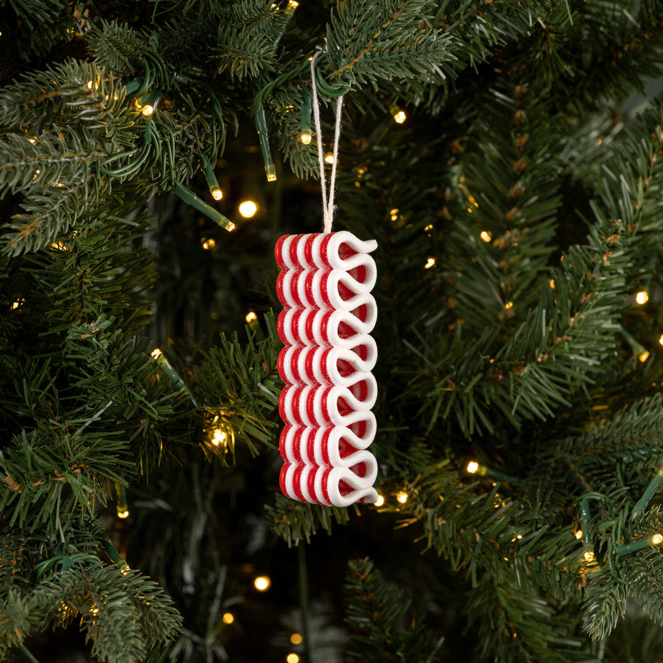 Red and white spiral Christmas ornament on a tree with lights
