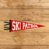 Red and white 'Ski Patrol' pennant on a wooden background