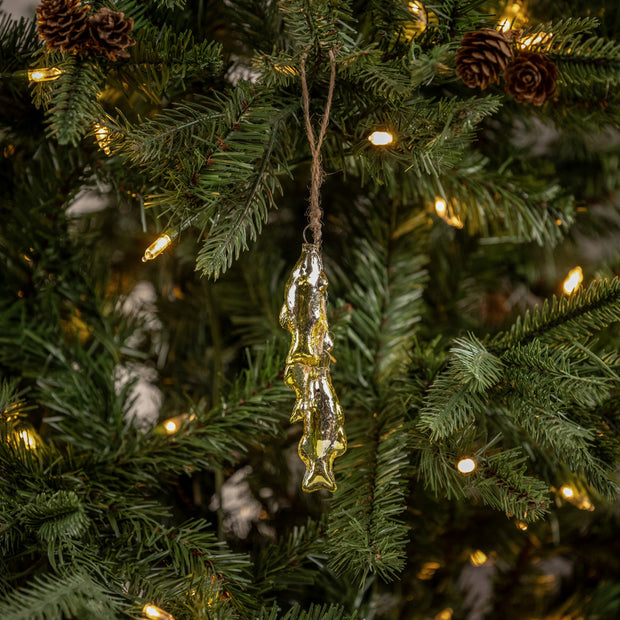 Decorative fish ornament hanging on a Christmas tree with lights and pinecones.