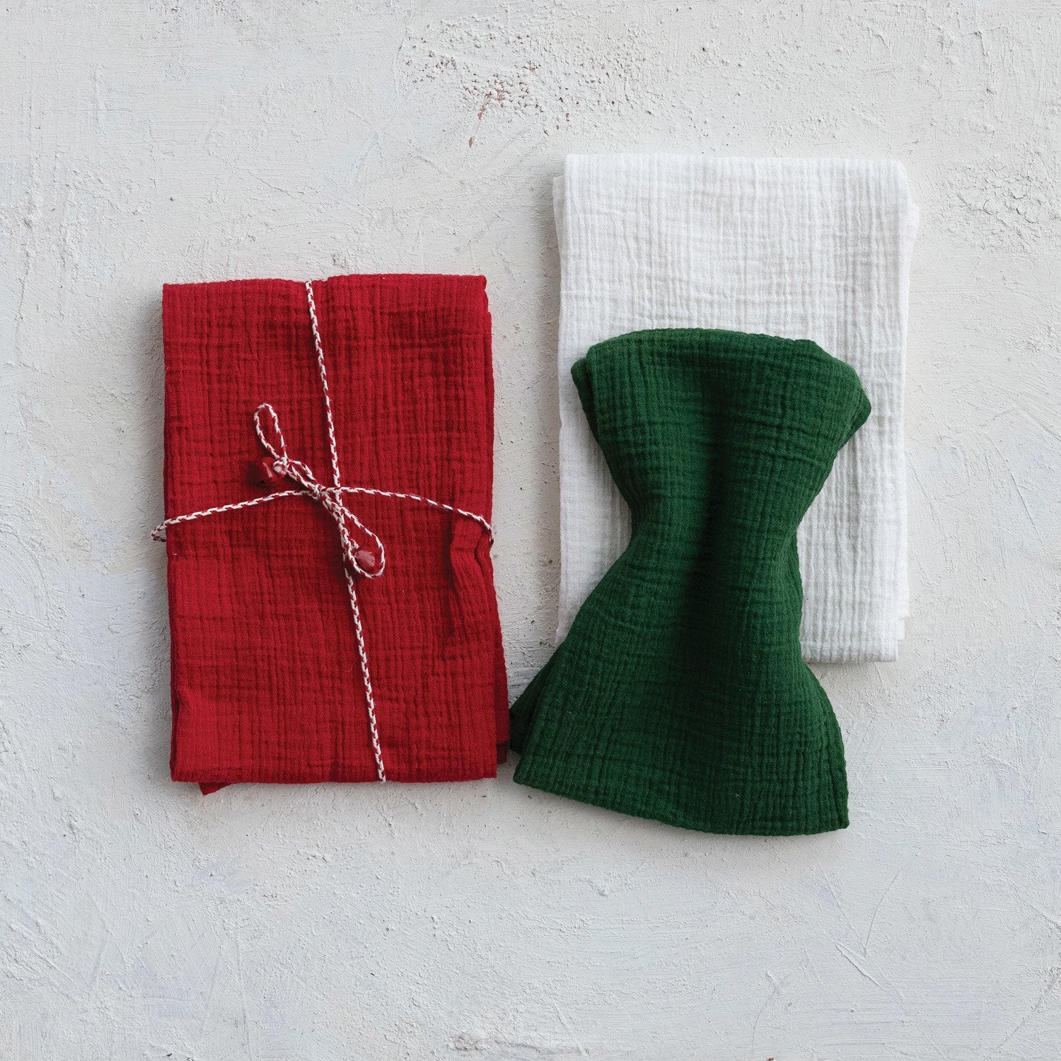 Red and green fabric items on a textured white surface