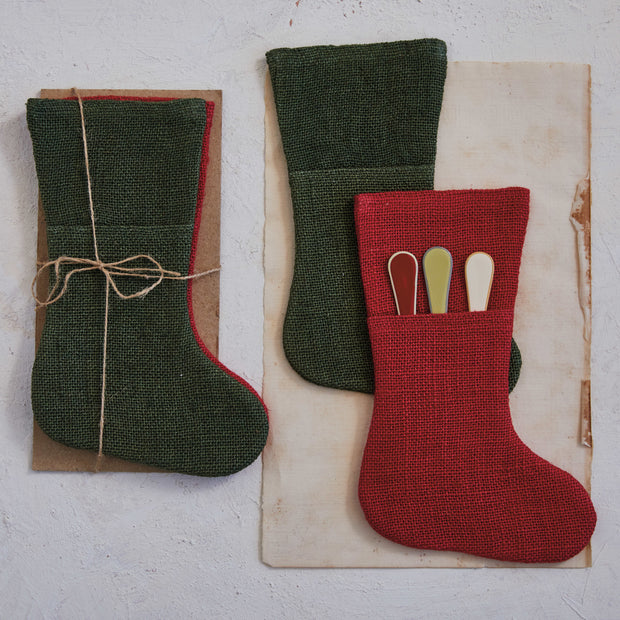 Two fabric stockings, one green and one red, on a textured surface.