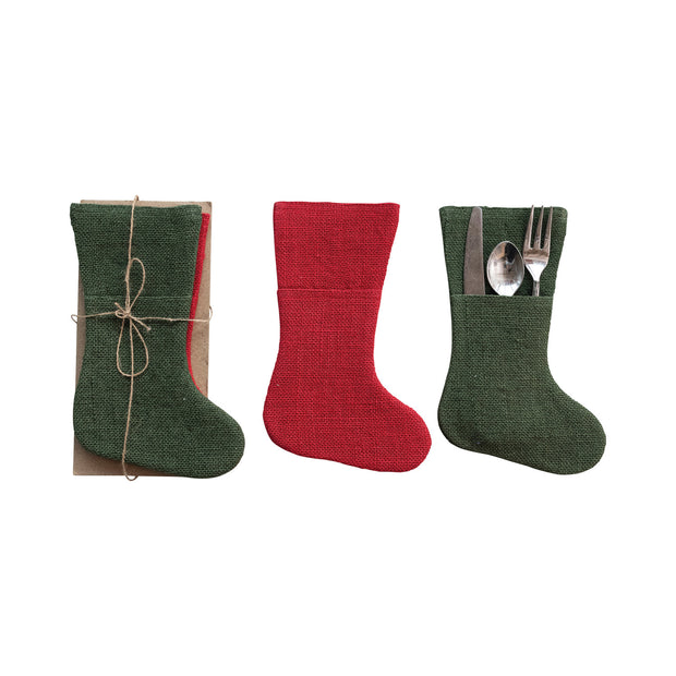 Three fabric stockings in green, red, and green with cutlery, on a white background.
