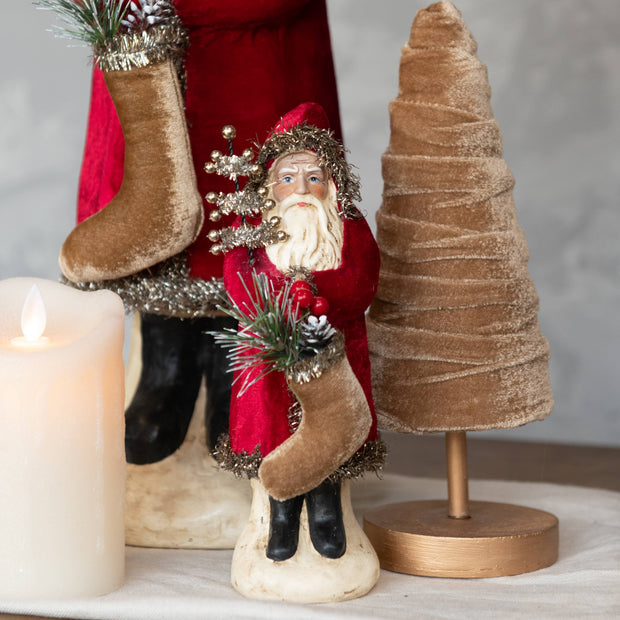 Decorative Christmas scene with a Santa figure, stockings, and a small tree.