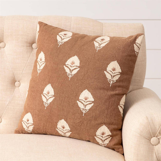 Brown pillow with white floral pattern on a beige sofa
