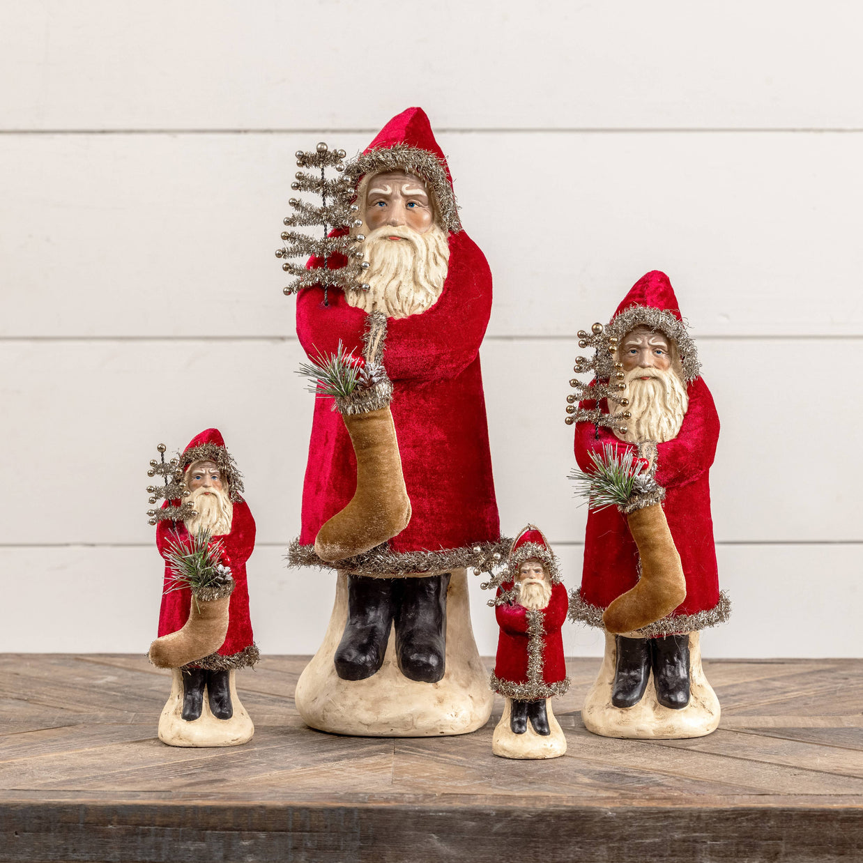Set of Santa Claus figurines with decorative elements on a wooden surface.