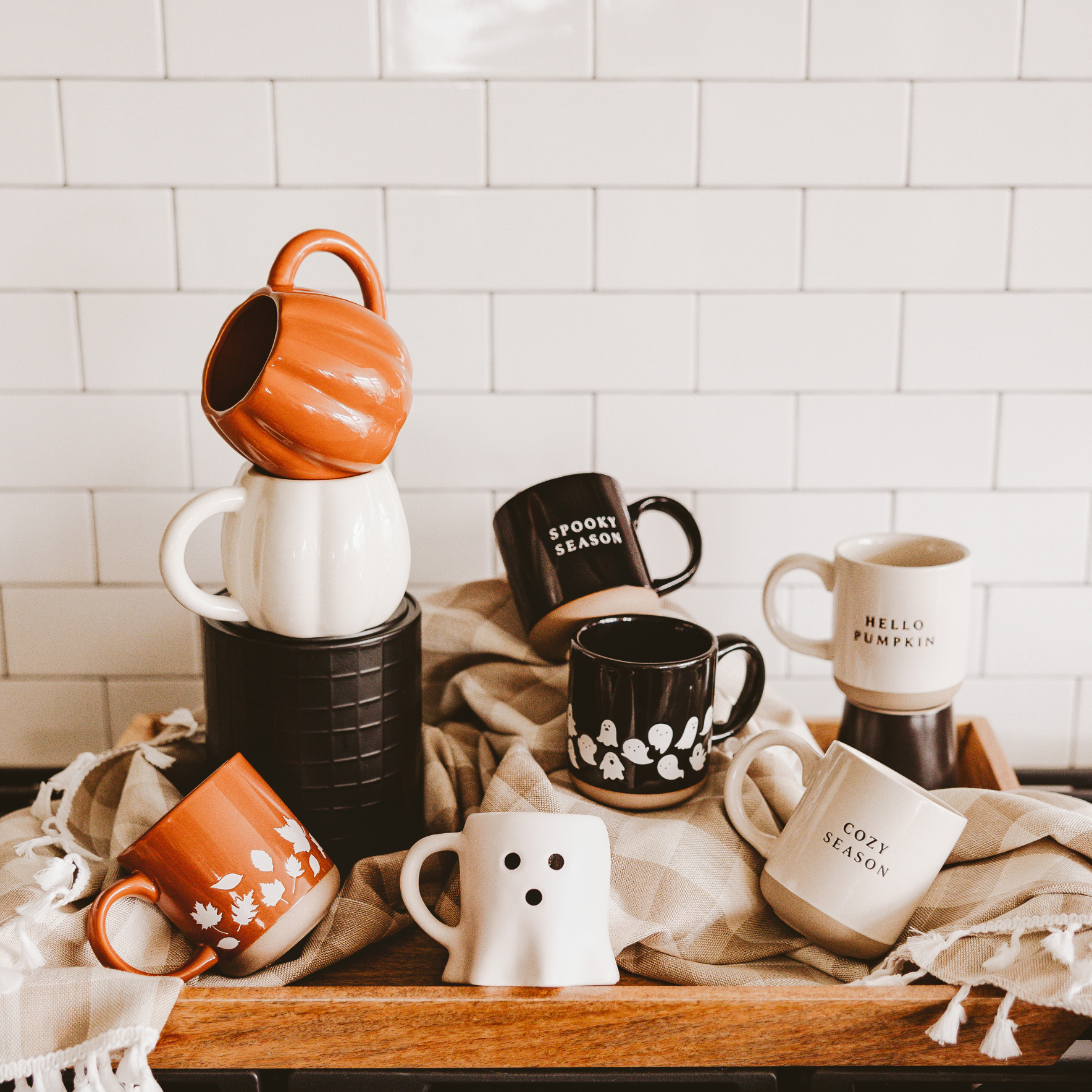 Collection of Halloween-themed mugs on a wooden tray with a tiled wall background