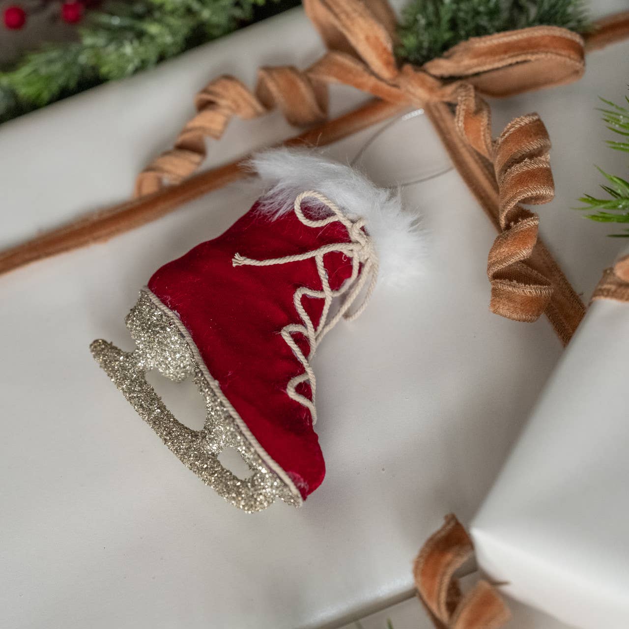 Red ice skate ornament on a white box with decorative ribbon