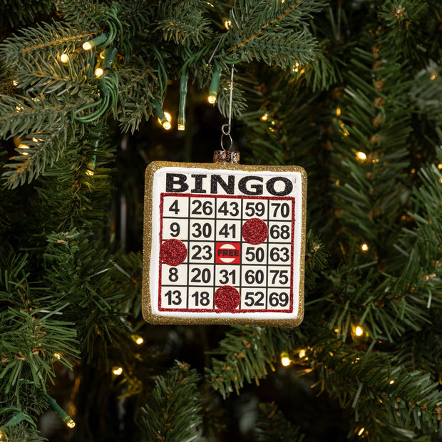 Bingo card ornament hanging on a Christmas tree with lights.