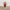 Decorative figure of a Santa Claus holding a bundle of sticks on a wooden surface.