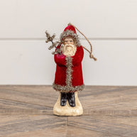 Decorative figure of a Santa Claus holding a bundle of sticks on a wooden surface.